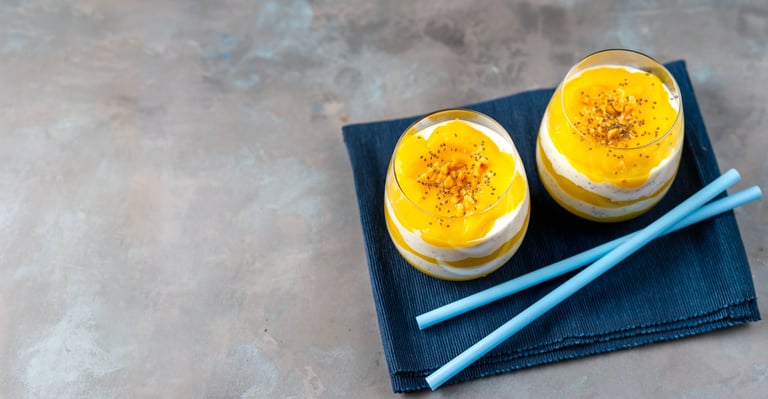 Mango and pineapple smoothie with yogurt in two glasses on white wooden table