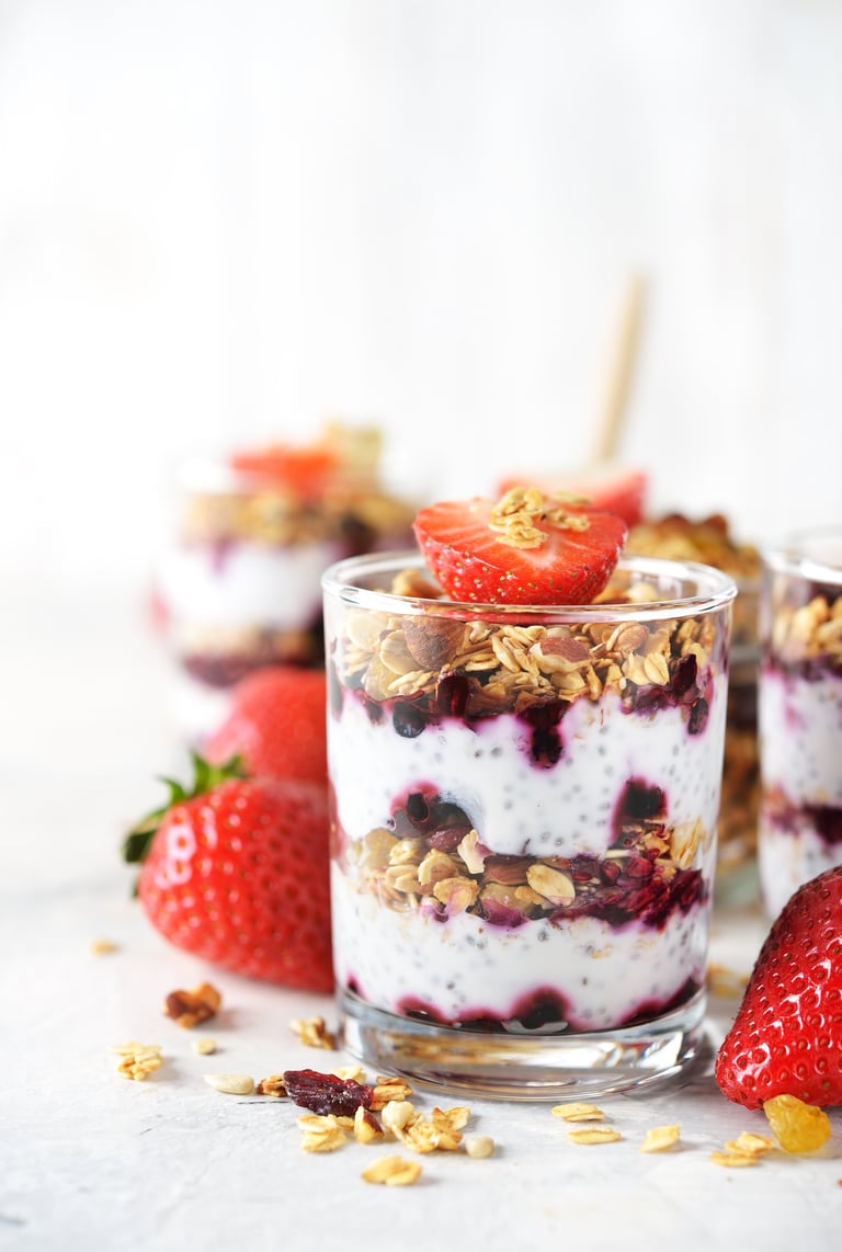 Dessert of homemade muesli, berries and yogurt in jars on a white background
