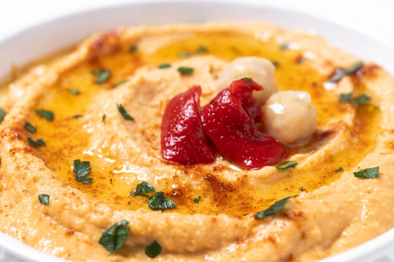 Roasted red pepper hummus in white bowl isolated on white background