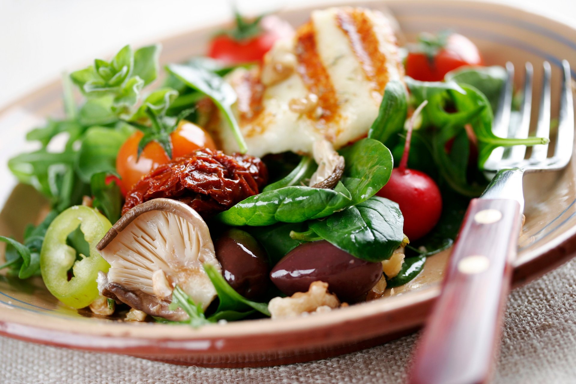 Salad with mushrooms, spinach, tomatoes, sundried tomatoes, walnuts, and haloumi cheese