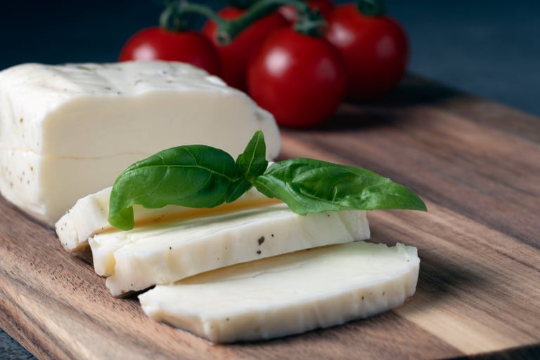 Close up of halloumi cheese slices with fresh basil and tomatoes in the background